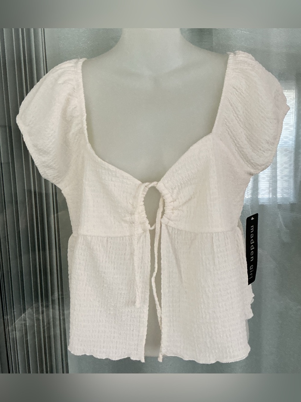 Cream babydoll top featuring short puff sleeves and a tie-front closure.